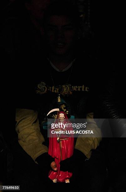 Young boy devotee of the 'Santa Muerte' , holds a figure of the goddess at the shrine in her honour in the popular Tepito shantytown, in Mexico City,...