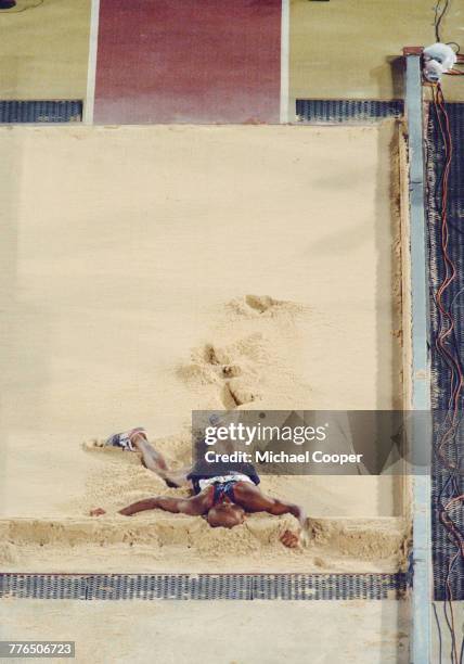 Mike Powell of the United States writhes in agony in the sand pit after injuring himself in the Men's Long Jump event on 29 July 1996 during the XXVI...
