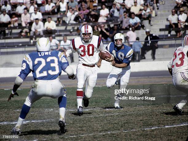 Boston Patriots defensive back Tom Hennessey runs back an interception as San Diego Chargers running back Paul Lowe and Hall of Fame wide receiver...