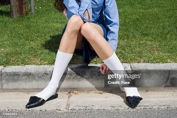 gawky girl wearing pointy shoes sitting on curb - mules shoes stock-fotos und bilder