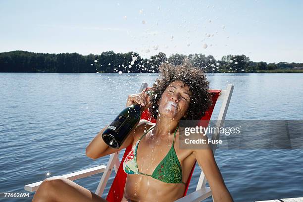 young woman on jetty spraying champagne - spraying champagne stock pictures, royalty-free photos & images