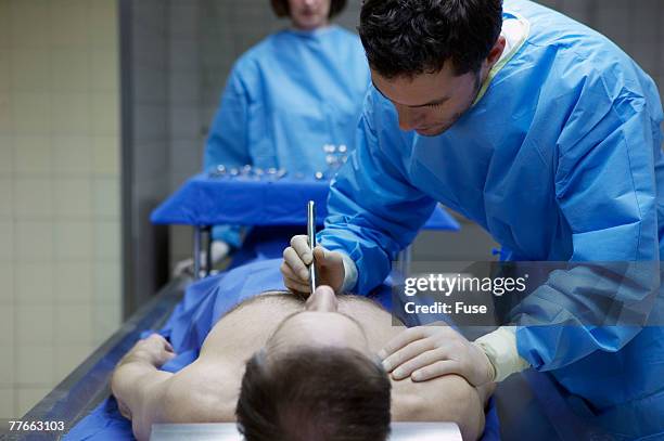 coroner examining body in morgue - autopsia fotografías e imágenes de stock