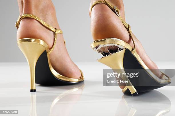 woman wearing gold shoes with broken heel - woman in broken shoe heel stockfoto's en -beelden