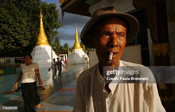 Burmese man smokes a cheroot, a Burmese hand rolled cigarette, at the Shwe Myin Won pagoda November 3, 2007 in Myawadi, Myanmar. United Nations envoy...