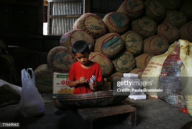 Gyi Kan packs tobacco into a Cheroot, a Burmese hand rolled cigarette, at a small family run Cheroot factory November 3, 2007 in Myawadi, Myanmar....