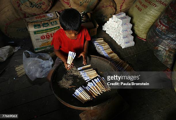 Gyi Kan packs tobacco into a Cheroot, a Burmese hand rolled cigarette, at a small family run Cheroot factory November 3, 2007 in Myawadi, Myanmar....