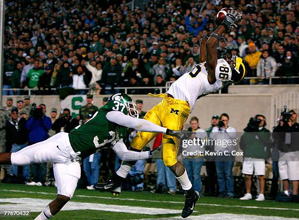 Receiver Mario Manningham of the Michigan Wolverines pulls in the game-winning touchdown against cornerback Ross Weaver of the Michigan State...