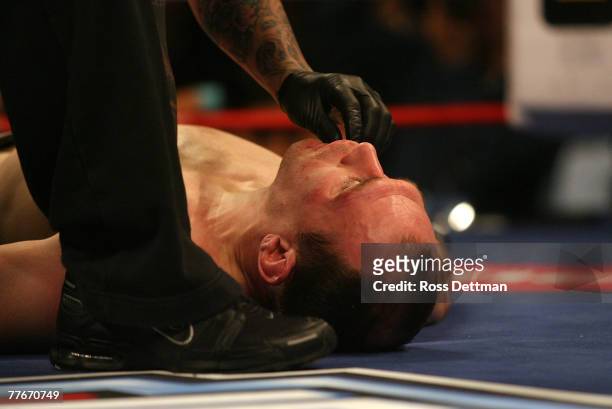 Brent Beauparlant of the Dragons is tended to as he lies on the canvas after being knocked out by Benji Radach of the Anacondas during their Middle...