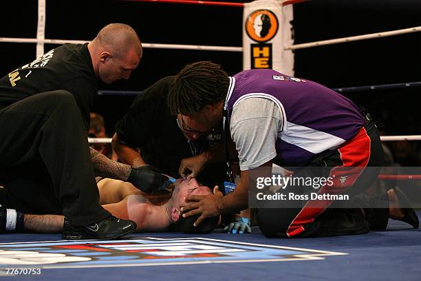 Brent Beauparlant of the Dragons is tended to as he lies on the canvas after being knocked out by Benji Radach of the Anacondas during their Middle...