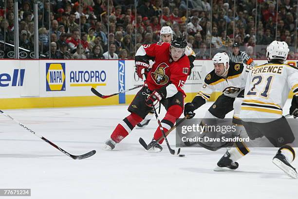 Dany Heatley of the Ottawa Senators carries the puck as Marco Sturm and Brad Ference both of the Boston Bruins defend during their NHL game at Scotia...