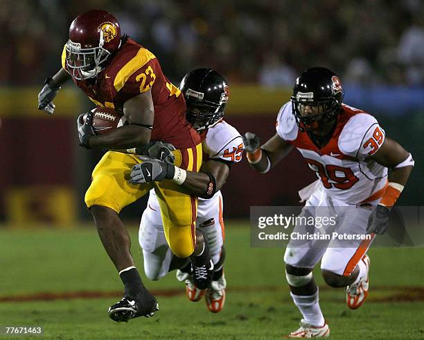 Runningback Chauncey Washington of the USC Trojans carries the ball for a 19 yard rush underpressure from Derrick Doggett and Daniel Drayton of the...