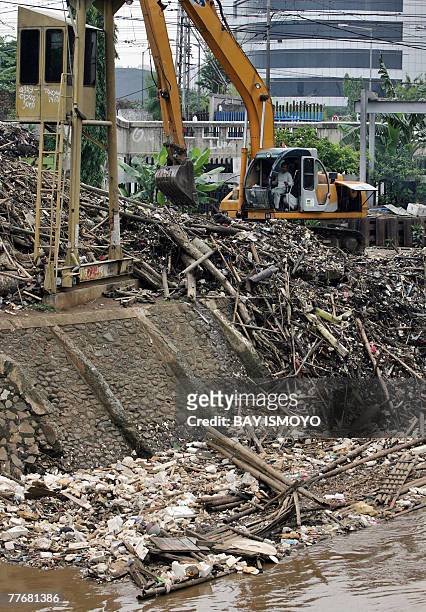 Man uses a back hoe to clean rubbish trapped at the flood dam in Jakarta, 05 November 2007. Experts say floods occurrs because of poor city planning...
