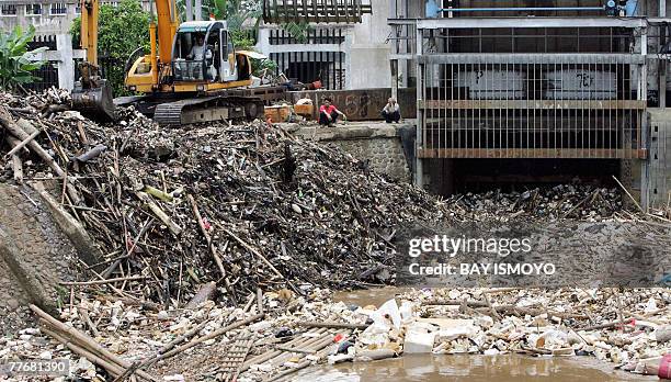 Man uses a back hoe to clean rubbish trapped at the flood dam in Jakarta, 05 November 2007. Experts say floods occurrs because of poor city planning...