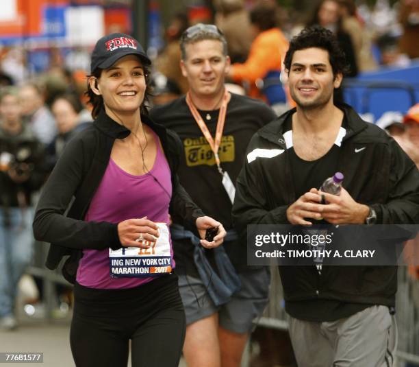 Actress Katie Holmes crosses the finish line and runs to her husband Tom Cruise and daughter Suri after she completed the New York City Marathon in...