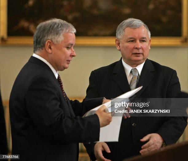 Polish Prime Minister Jaroslaw Kaczynski hands his resignation documents to his twin brother President Lech Kaczynski, during a ceremony at the...