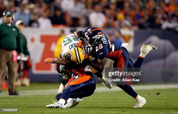 Running back Ryan Grant of the Green Bay Packers holds onto the ball as he is hit by safety Nick Ferguson of the Denver Broncos at Invesco Field at...