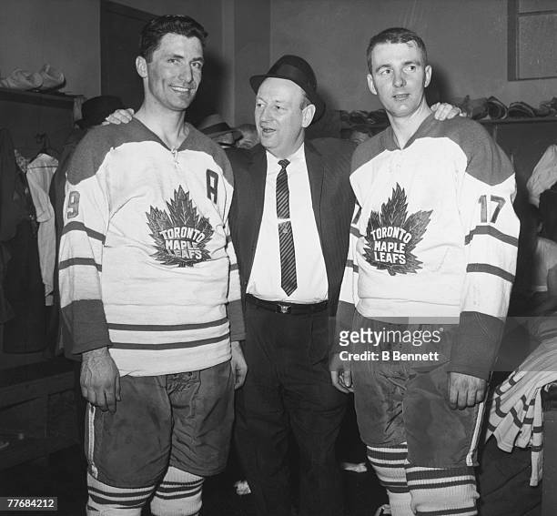 Canadian ice hockey coach Punch Imlach of the Toronto Maple Leafs poses with two of his players, Andy Bathgate and Don McKenney, in the locker room...