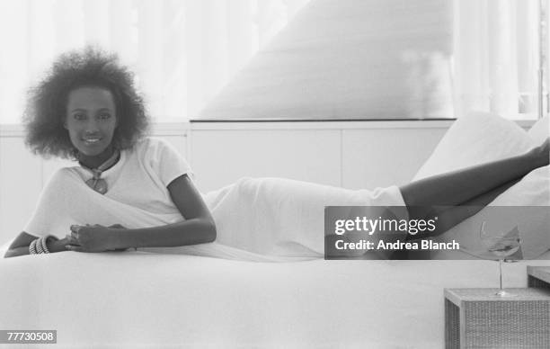 Portrait of Somali-born American actress and model Iman as she lies on a bed, her feet on the pillow, from a photoshoot for the American edition of...