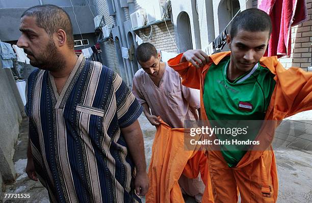 Iraqi men who've been chosen to appear before an Iraqi judge to be arraigned put on orange jumpsuits for the trip to the court November 6, 2007 in...