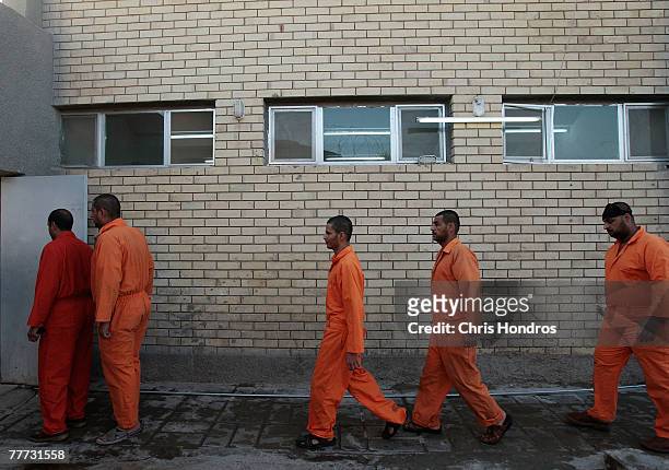 Arrested Iraqi men who've been chosen to appear before an Iraqi judge to be arraigned line up in orange jumpsuits to make the trip to court November...