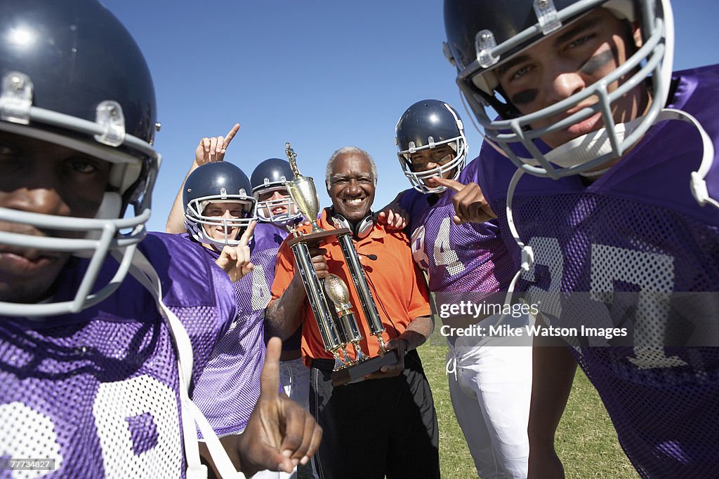 Happy Football Coach with Trophy and Players