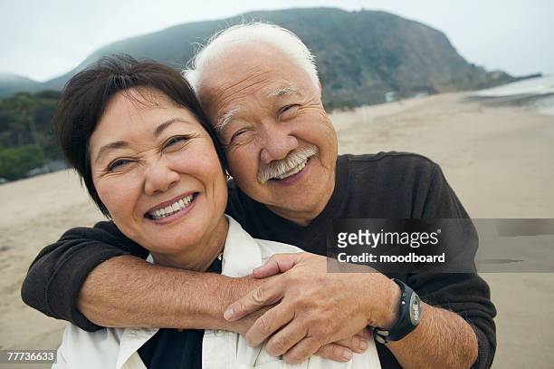 happy mature couple hugging on beach - asian senior couple stock pictures, royalty-free photos & images