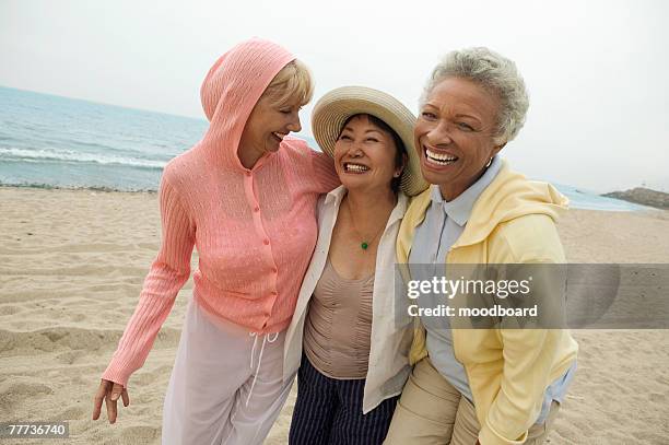 friends walking together at beach - mature women friendship stock pictures, royalty-free photos & images