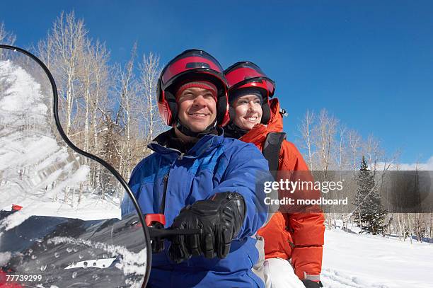 couple sitting on snowmobile - man wearing helmet stock pictures, royalty-free photos & images