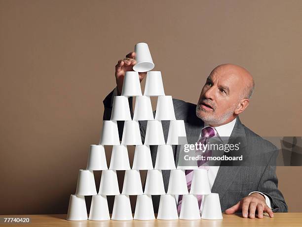 businessman building pyramid of cups - 三角錐 ストックフォトと画像