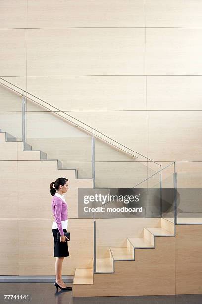 businesswoman standing at bottom of stairway - karriereleiter stock-fotos und bilder