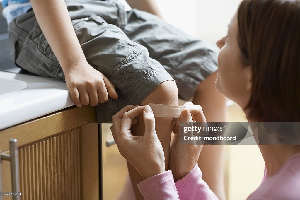 Mother Applying Bandage to Sons Knee