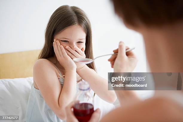 mother giving daughter cough syrup - cough syrup stock pictures, royalty-free photos & images