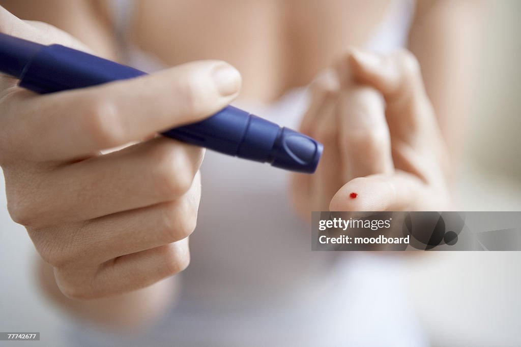 Woman Performing Blood Test on Herself