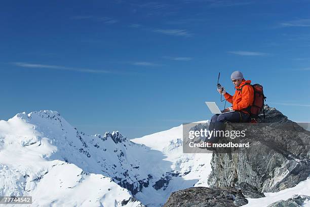 mountaineer using laptop and satellite phone - digital handhold device stock pictures, royalty-free photos & images
