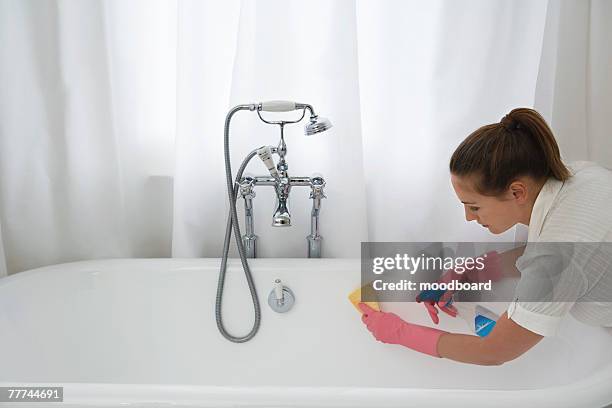young woman scrubbing bathtub - drudgery stock pictures, royalty-free photos & images