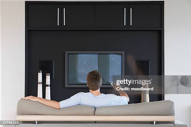 man watching tv - back of sofa stock pictures, royalty-free photos & images