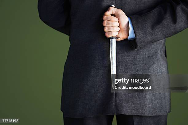 businessman holding knife behind back - trama fotografías e imágenes de stock