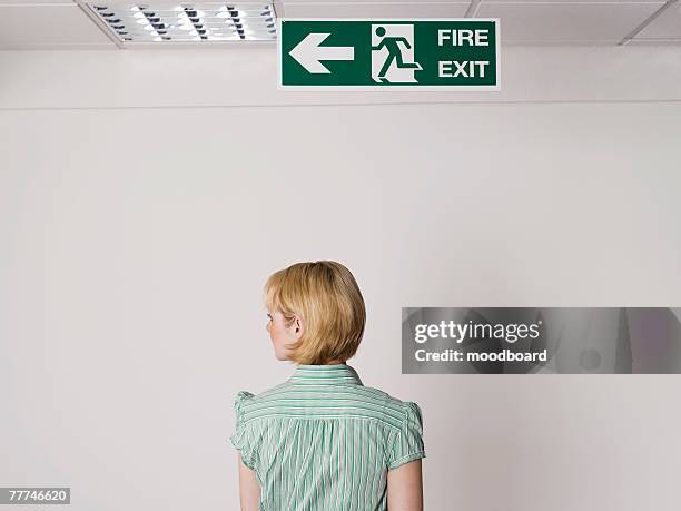 businesswoman standing under exit sign - escaping office stock pictures, royalty-free photos & images