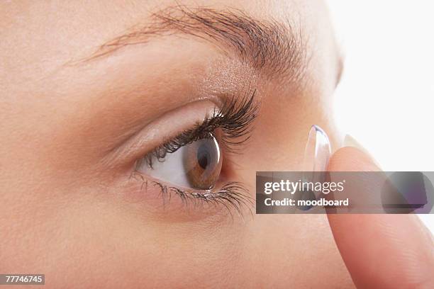 young woman putting in contact lens - eye lens stock pictures, royalty-free photos & images