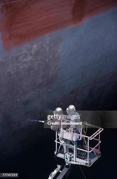 two people painting a large ship - mismatch stock-fotos und bilder