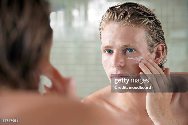 man applying facial cream - crema viso foto e immagini stock