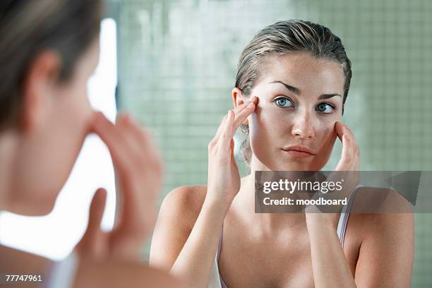 woman applying facial cream - beauty mirror imagens e fotografias de stock