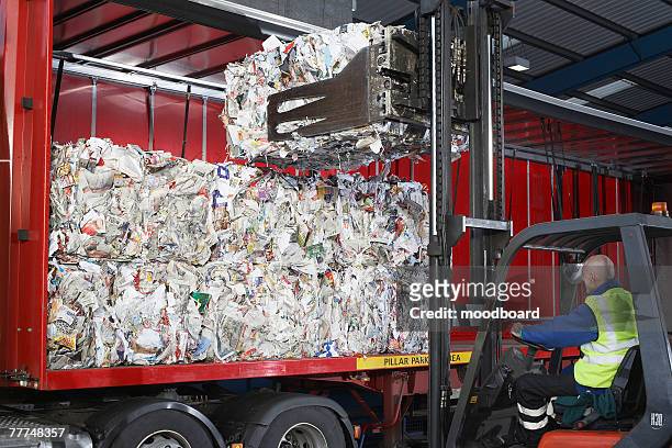 forklift driver loading recovered paper on truck - garbage truck stock-fotos und bilder