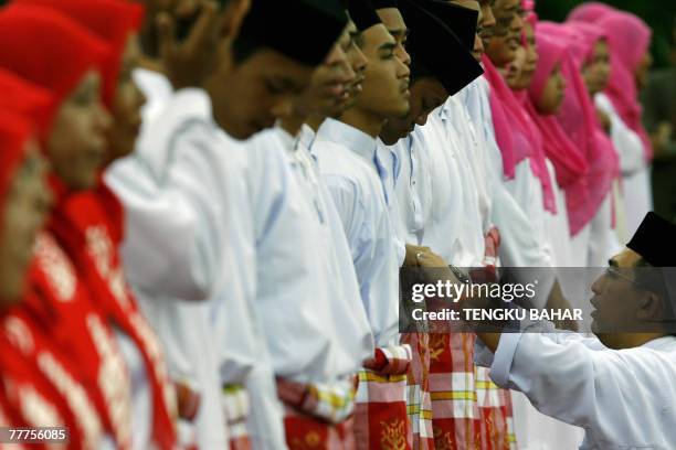 Guard of honour member of the ruling United Malays National Organisation party adjusts a comrade's traditional "baju Melayu" costume as they await...