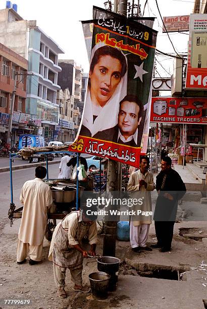 Street cook washes his plates under a Pakistan People's Party poster in a street in Rawalpindi, Pakistan on November 8, 2007. Bhutto plans to hold a...