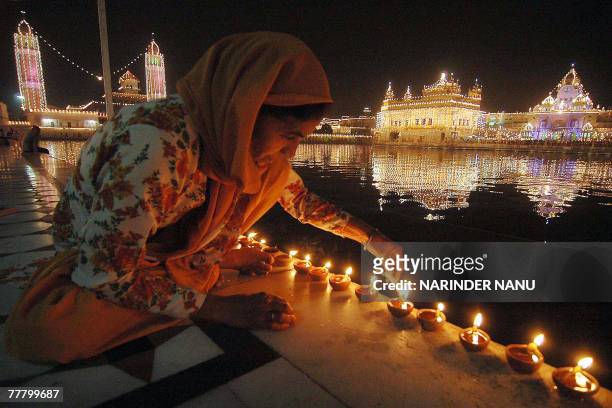 Indian devotees light candles in front of the illuminated Golden temple in Amritsar, on the eve of Bandi Chhor Divas in Amritsar, 08 November 2007....