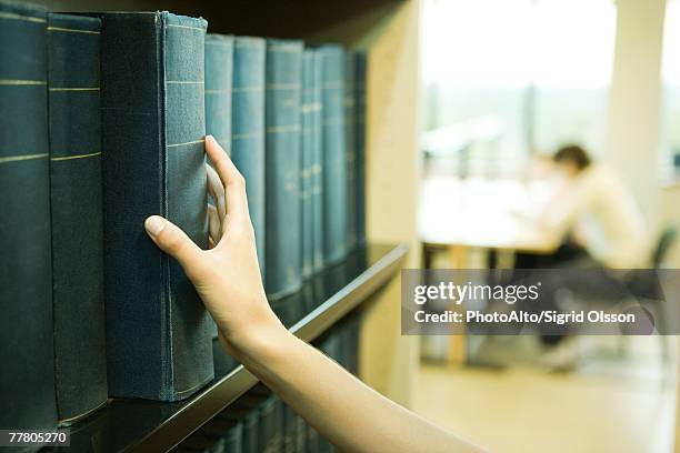 female student taking reference book from shelf in library - enciclopedia stock pictures, royalty-free photos & images