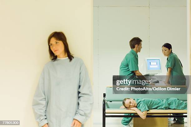 medical workers chatting in office, one lying down on bench, female patient standing in foreground - body lying down stock pictures, royalty-free photos & images