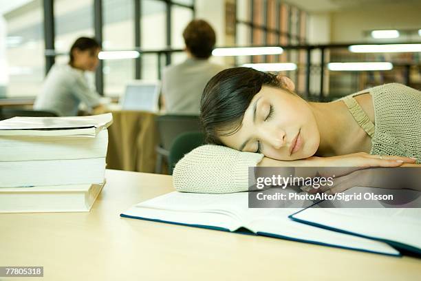 young woman in university library, head on arm, asleep - manuel scolaire photos et images de collection
