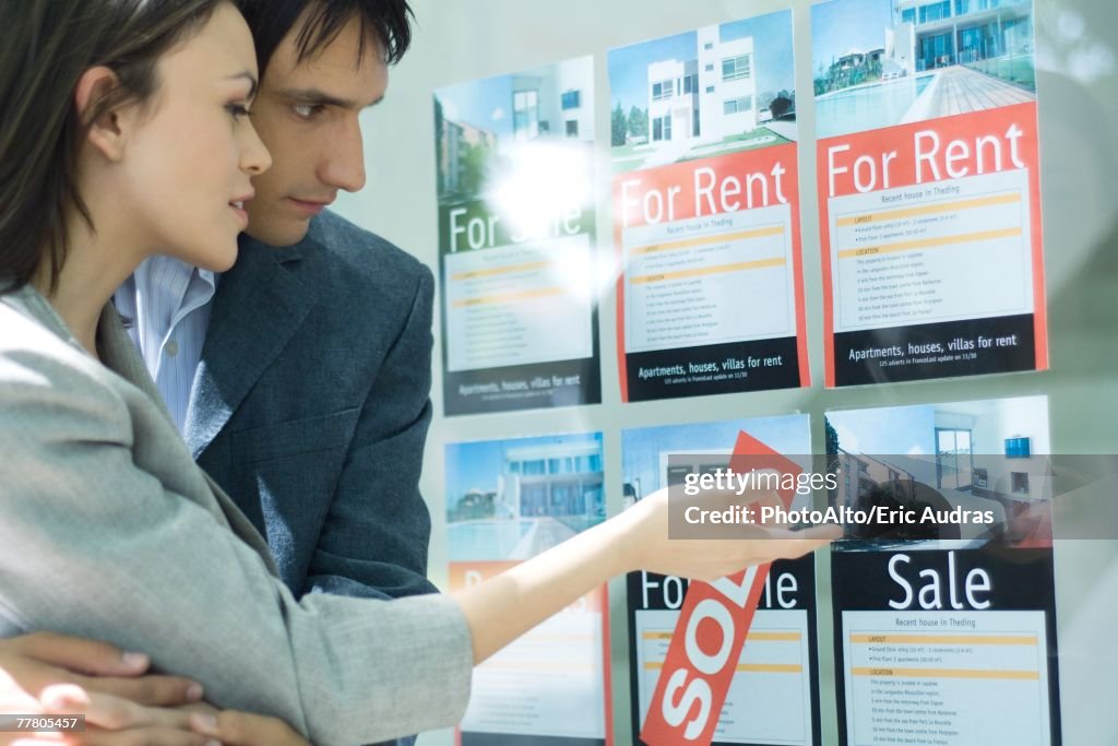 Couple looking at properties in window of real estate agency
